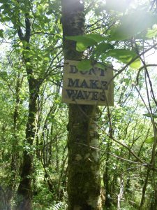 ceramic letters spelling "don't make waves" attached to a tree
